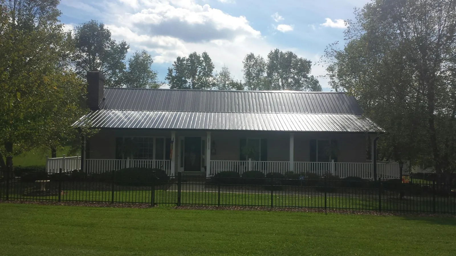 Gray metal roof on a brick ranch with a full width front porch — Gutter Guard Installation work by our crew in Santa Fe