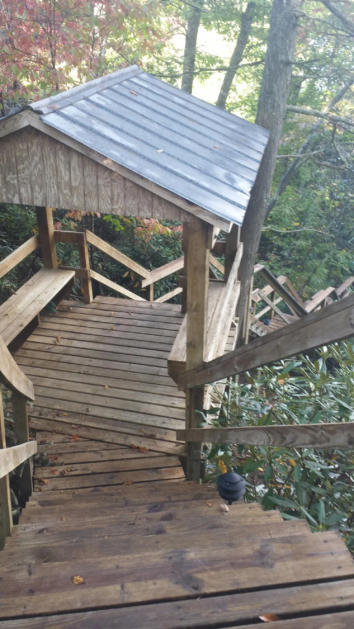 Metal roofed shelter over wooden steps on a wooded walkway — Skylight Repair & Installation work by our crew in Santa Fe